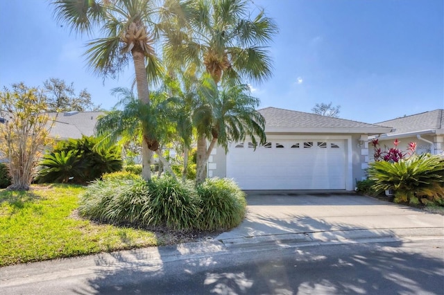 view of property hidden behind natural elements with a garage, driveway, and stucco siding