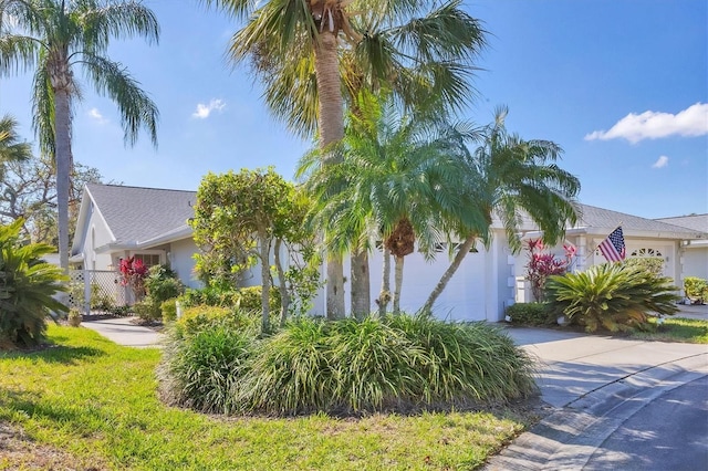 view of property hidden behind natural elements featuring a garage, driveway, and stucco siding