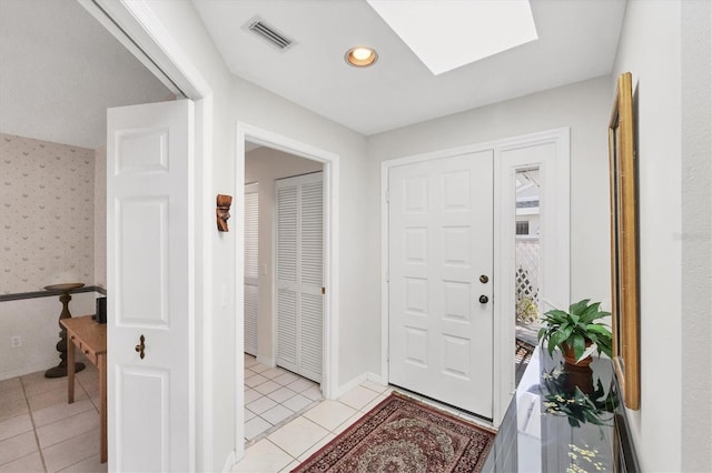 entrance foyer featuring a skylight, wallpapered walls, baseboards, visible vents, and light tile patterned flooring