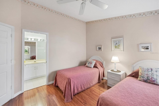 bedroom featuring a ceiling fan, baseboards, ensuite bath, and wood finished floors