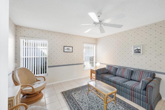 living room featuring wallpapered walls, a wainscoted wall, ceiling fan, tile patterned flooring, and a textured ceiling