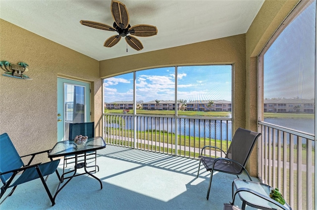 sunroom featuring a water view and a ceiling fan