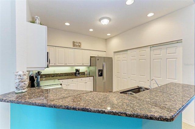 kitchen with a peninsula, appliances with stainless steel finishes, dark stone countertops, and white cabinetry