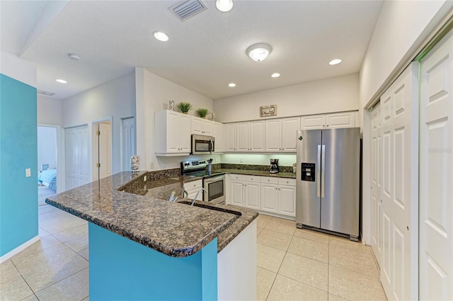 kitchen featuring a peninsula, appliances with stainless steel finishes, light tile patterned flooring, and visible vents