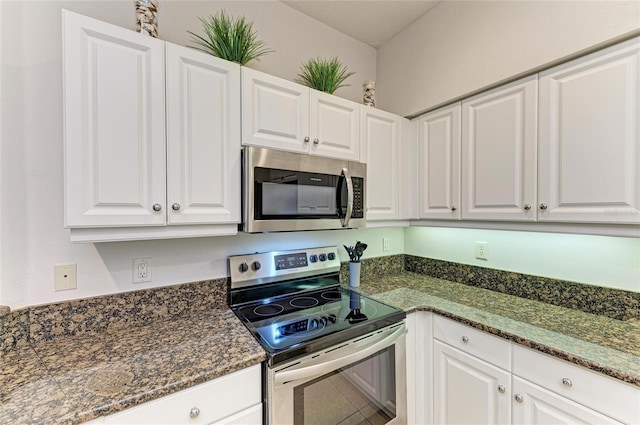 kitchen featuring dark stone counters, stainless steel appliances, and white cabinetry