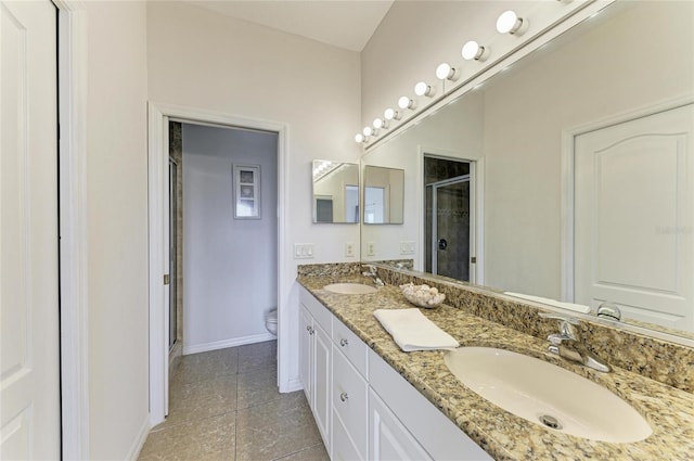 bathroom with a stall shower, toilet, a sink, and baseboards