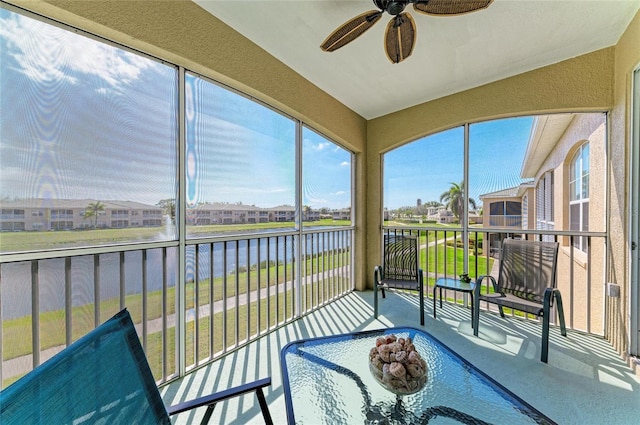 sunroom featuring a water view, a residential view, and a ceiling fan