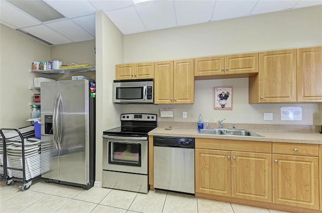 kitchen featuring light tile patterned floors, stainless steel appliances, light countertops, a sink, and a drop ceiling