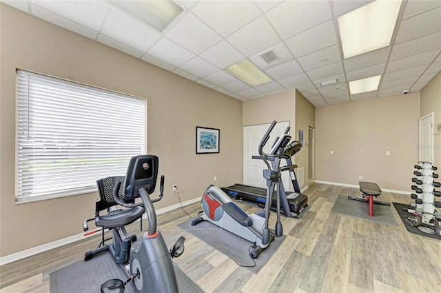 workout room with a drop ceiling, wood finished floors, visible vents, and baseboards