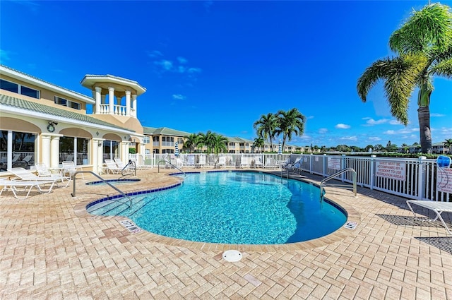 community pool with a patio and fence