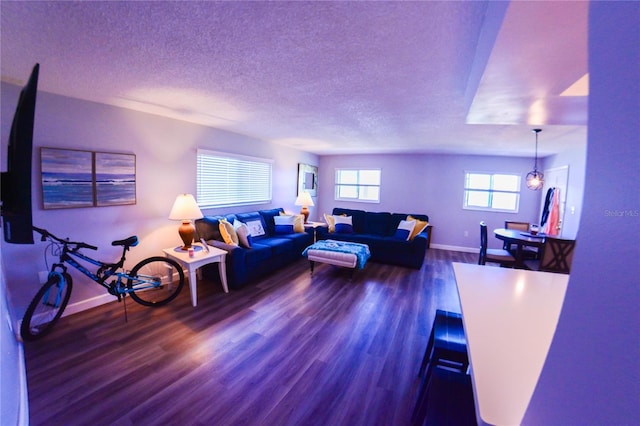 living room featuring a textured ceiling, baseboards, and wood finished floors