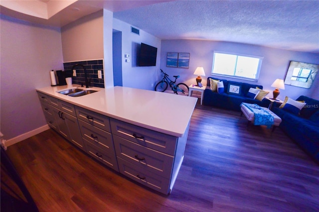 kitchen featuring dark wood-style floors, visible vents, a peninsula, a sink, and light countertops