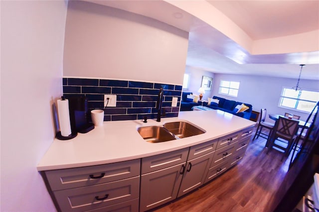 kitchen featuring dark wood-style flooring, a sink, decorative backsplash, light countertops, and hanging light fixtures