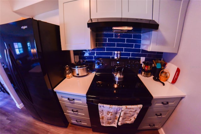 kitchen featuring black appliances, backsplash, light countertops, and under cabinet range hood