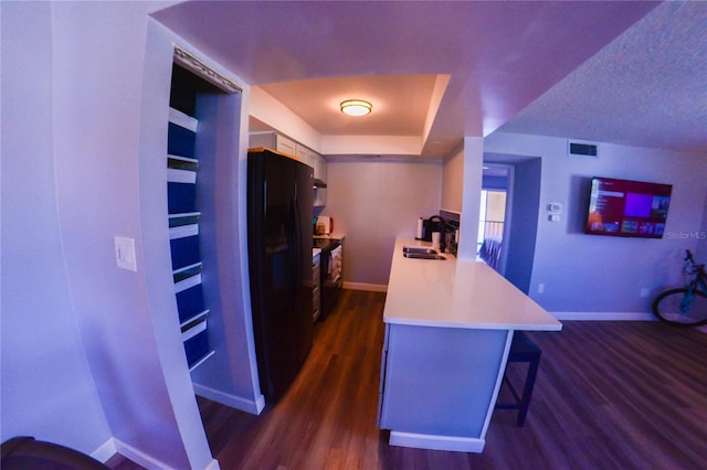 kitchen with a breakfast bar, dark wood-type flooring, light countertops, and baseboards