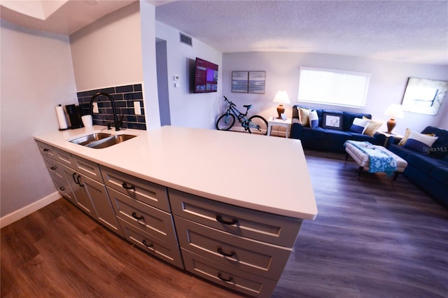 kitchen featuring visible vents, a sink, open floor plan, dark wood finished floors, and a peninsula