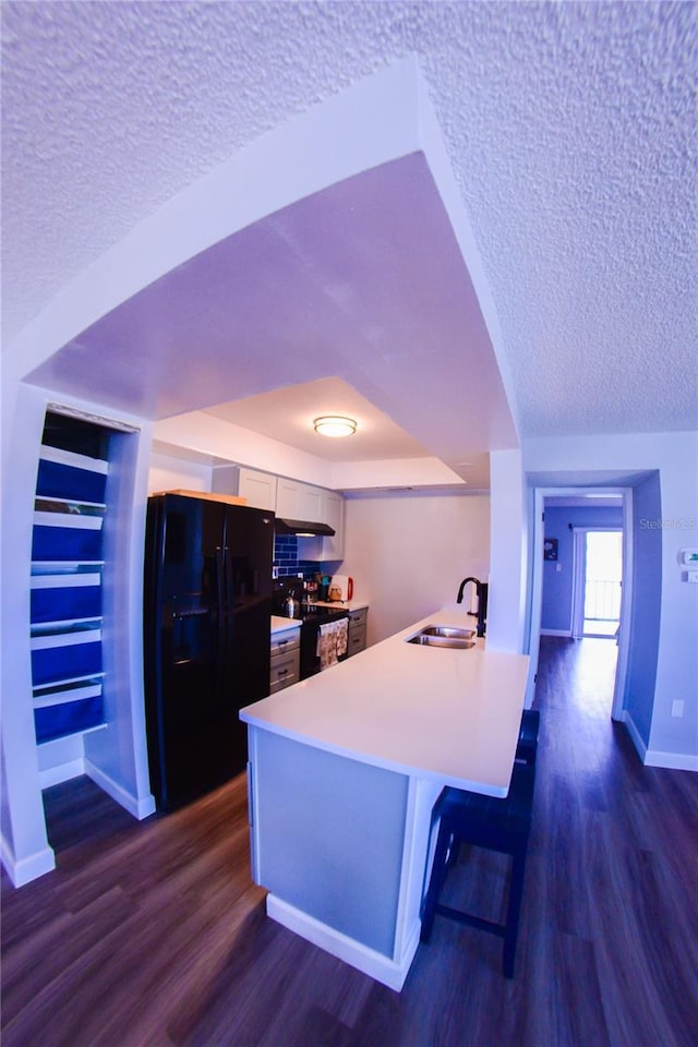 kitchen with dark wood-style floors, a textured ceiling, black appliances, and a sink