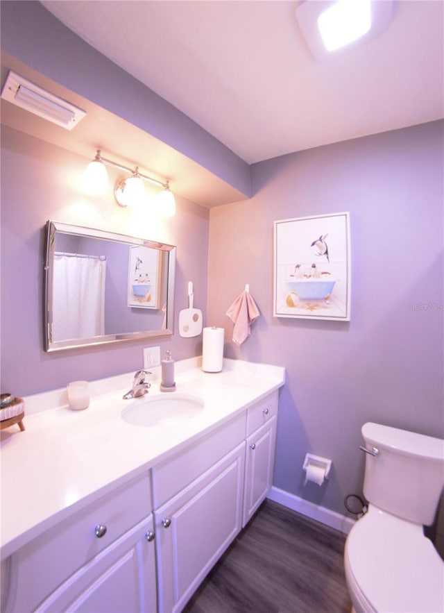 full bath featuring vanity, wood finished floors, visible vents, baseboards, and toilet