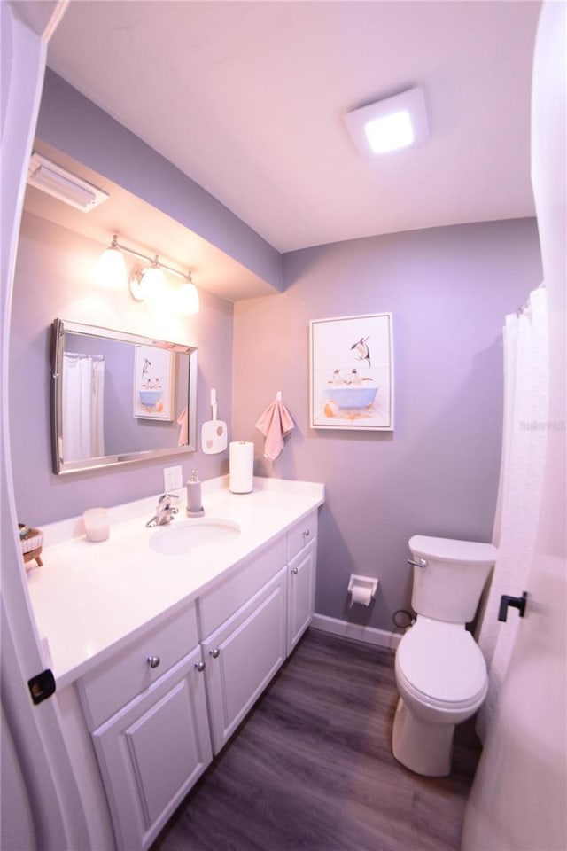 full bathroom with baseboards, toilet, wood finished floors, and vanity