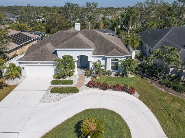 view of front of house featuring an attached garage, a shingled roof, driveway, stucco siding, and a front yard