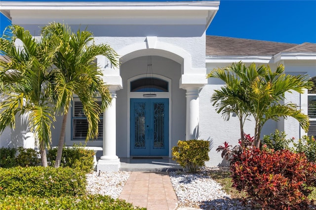 doorway to property featuring stucco siding, a shingled roof, and french doors