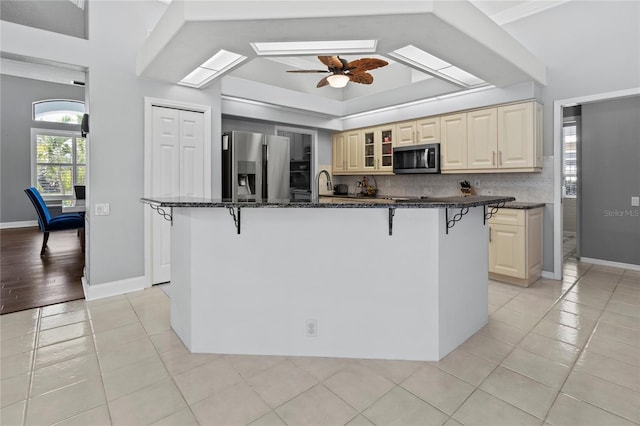 kitchen featuring light tile patterned floors, appliances with stainless steel finishes, a skylight, and a breakfast bar