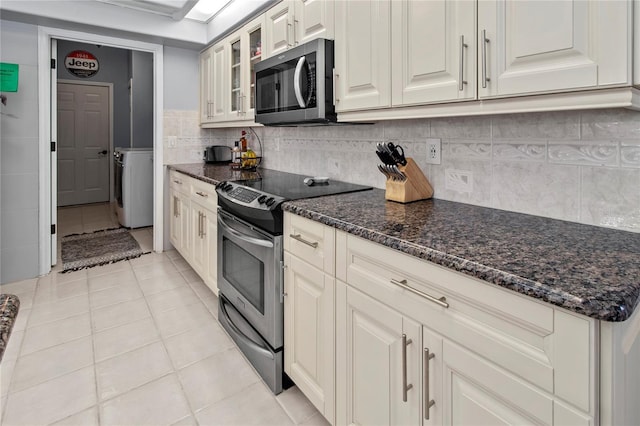 kitchen featuring light tile patterned floors, stainless steel appliances, washer / clothes dryer, glass insert cabinets, and tasteful backsplash