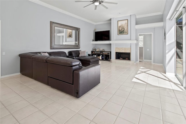 living room featuring a ceiling fan, a tile fireplace, crown molding, and light tile patterned floors