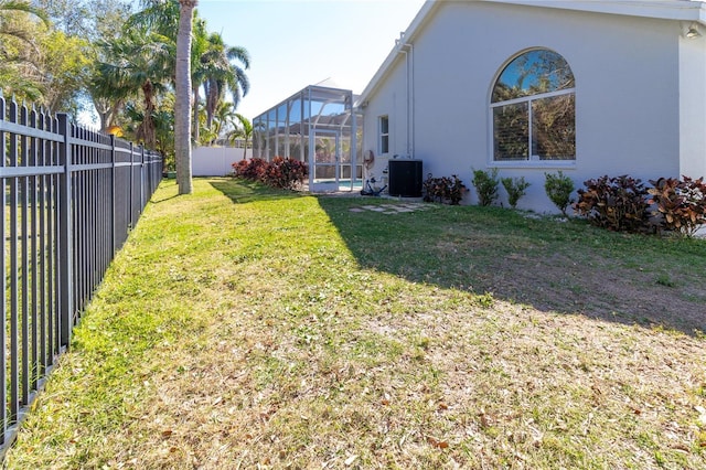 view of yard featuring a lanai, a fenced backyard, and central air condition unit