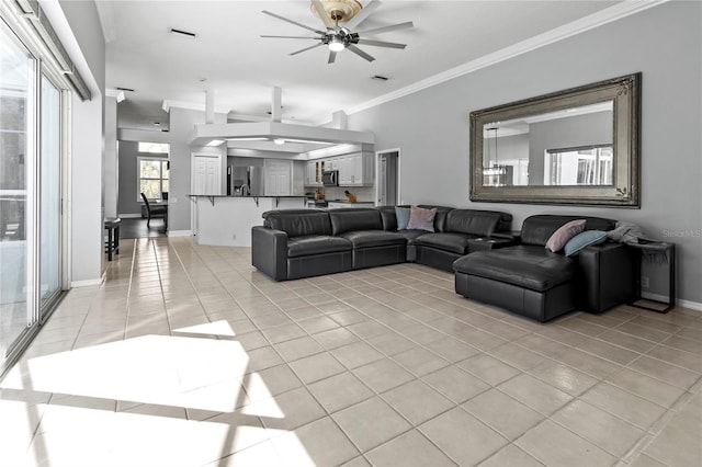 living room featuring light tile patterned floors, visible vents, baseboards, ceiling fan, and ornamental molding