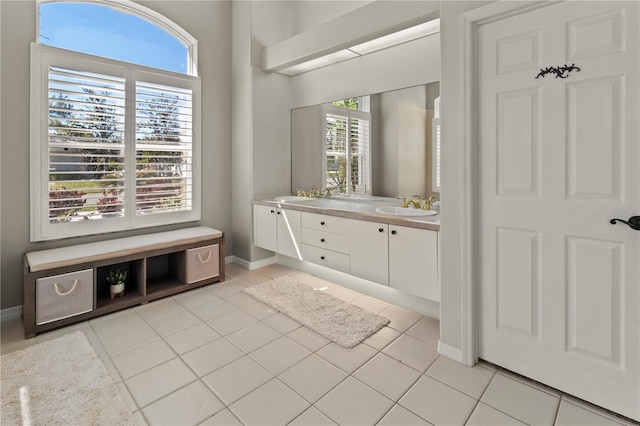 full bathroom with baseboards, double vanity, a sink, and tile patterned floors