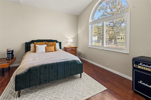 bedroom with vaulted ceiling, wood finished floors, and baseboards