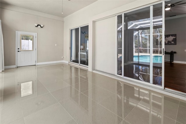 interior space featuring a ceiling fan, tile patterned flooring, a sunroom, and baseboards