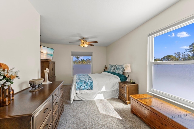 bedroom with multiple windows, ceiling fan, and light carpet