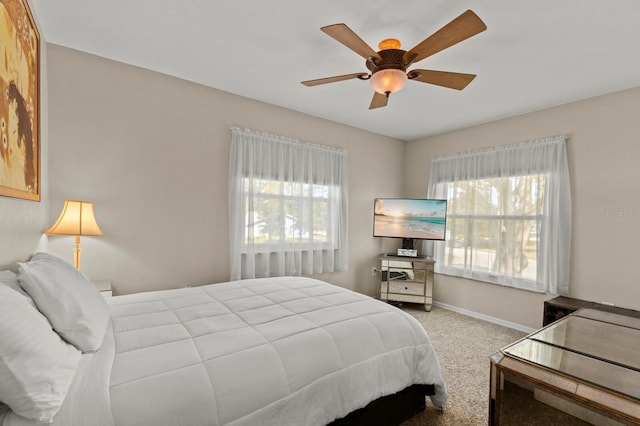 carpeted bedroom featuring multiple windows, baseboards, and a ceiling fan