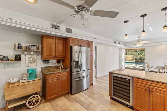 kitchen with wine cooler, light stone counters, brown cabinetry, and stainless steel fridge with ice dispenser