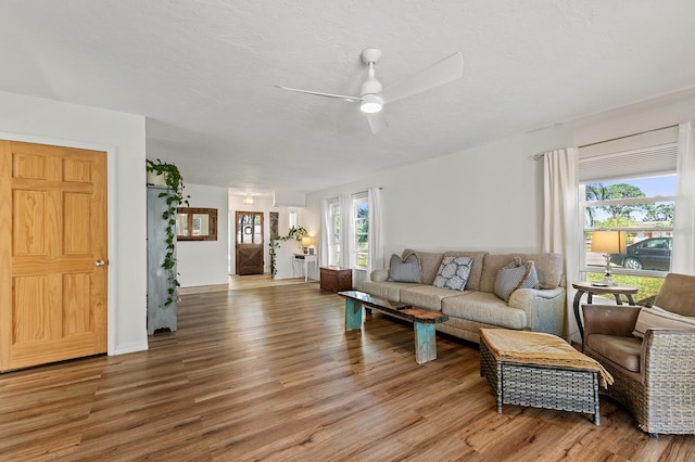 living room with light wood-style floors, ceiling fan, and a textured ceiling