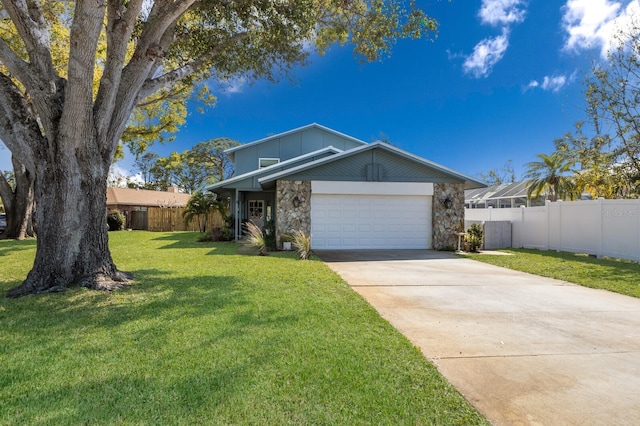 mid-century inspired home featuring a garage, fence, concrete driveway, stone siding, and a front lawn