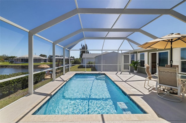 pool with glass enclosure, a patio area, and a water view