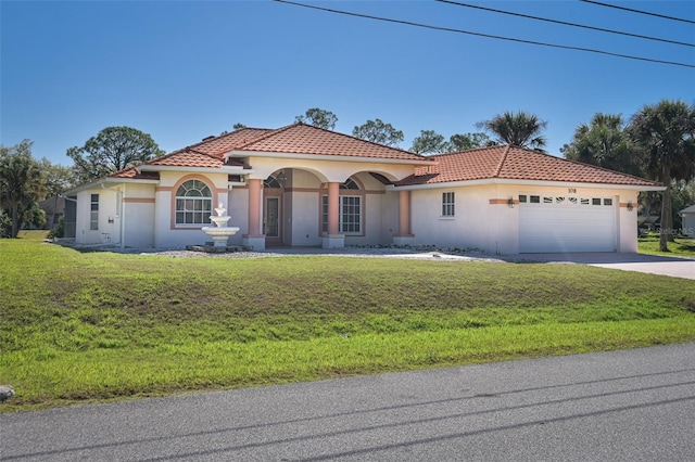 mediterranean / spanish-style home with a front lawn, a tiled roof, stucco siding, driveway, and an attached garage