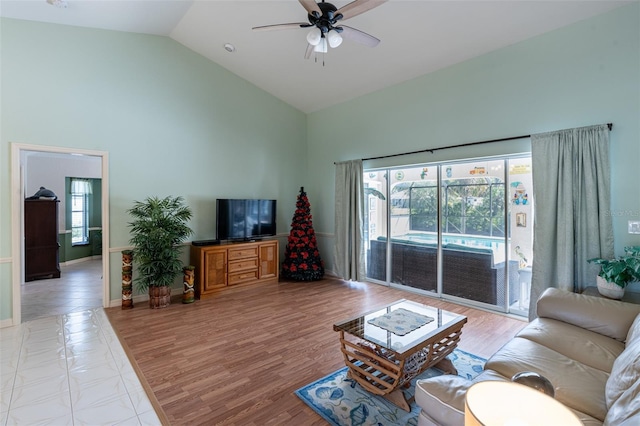 living room featuring a ceiling fan, baseboards, light wood finished floors, and high vaulted ceiling