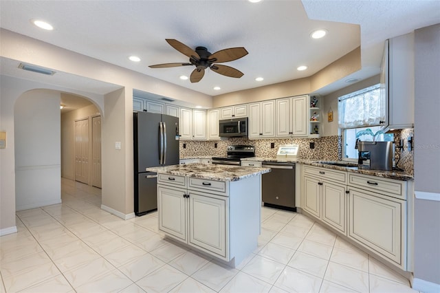 kitchen featuring arched walkways, backsplash, appliances with stainless steel finishes, and ceiling fan