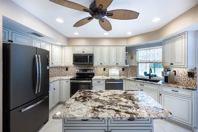 kitchen with light stone countertops, a ceiling fan, a sink, decorative backsplash, and appliances with stainless steel finishes