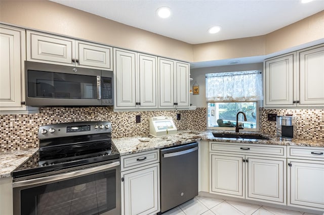 kitchen with backsplash, light stone counters, recessed lighting, stainless steel appliances, and a sink