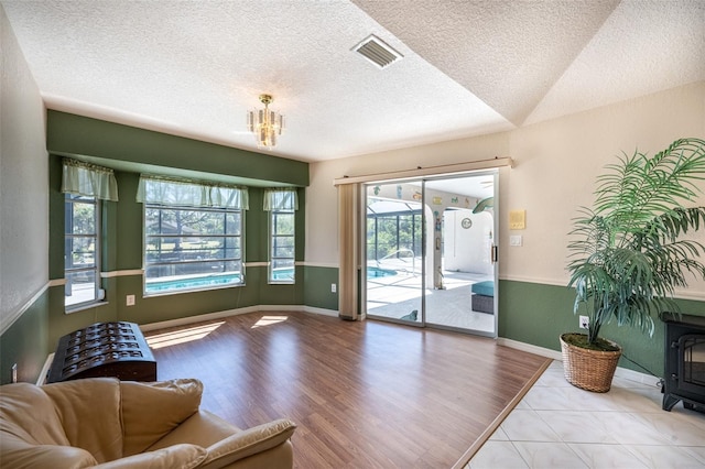 living area featuring a notable chandelier, wood finished floors, visible vents, and a textured ceiling