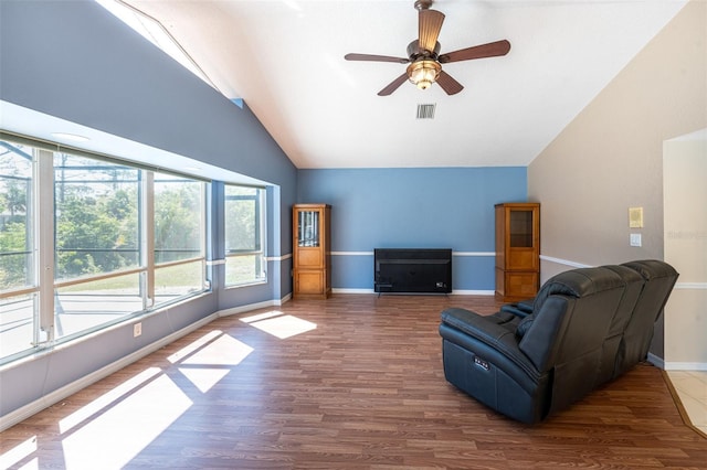 sitting room with wood finished floors, visible vents, a ceiling fan, baseboards, and high vaulted ceiling