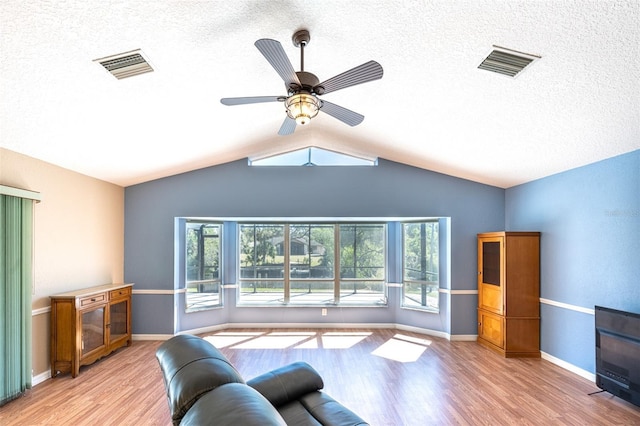 living area with a wealth of natural light, visible vents, and wood finished floors