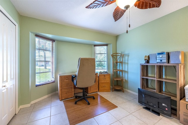 office space with light tile patterned flooring, a ceiling fan, and baseboards