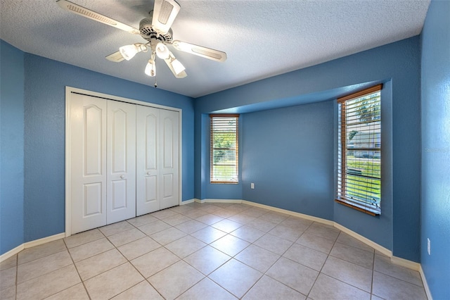 unfurnished bedroom featuring light tile patterned floors, baseboards, a closet, and ceiling fan