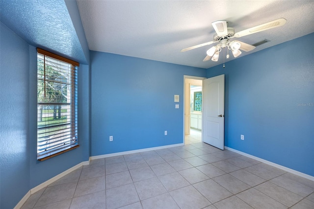 spare room featuring visible vents, baseboards, light tile patterned flooring, and a ceiling fan